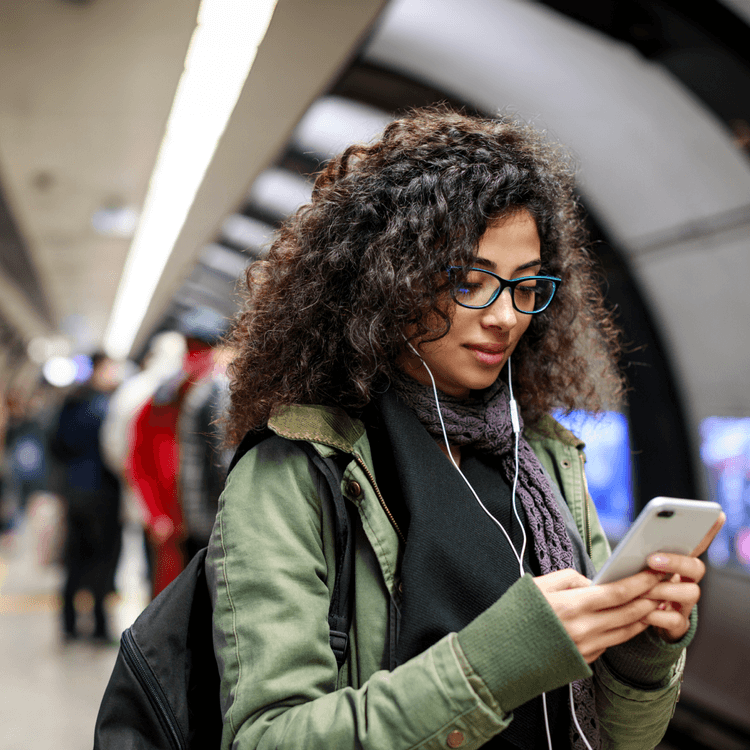 A woman standing in a train station whilst on her phone
