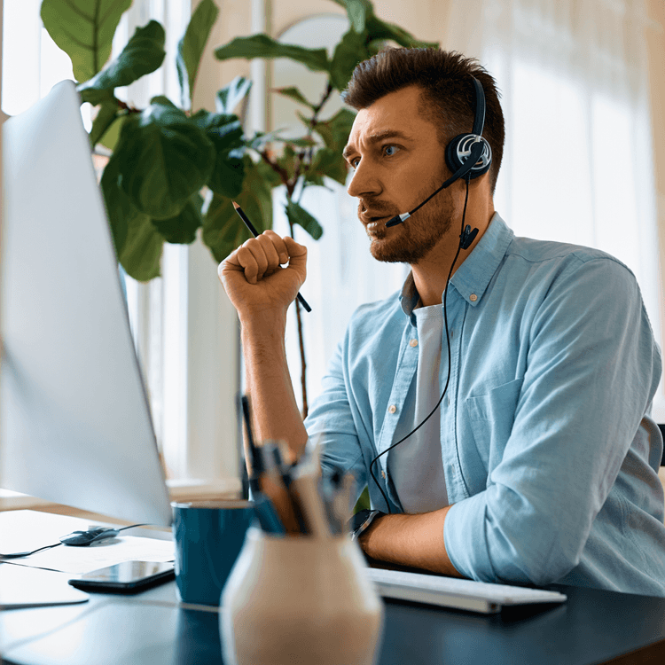 A man sitting at a desk on a phone call on his computer