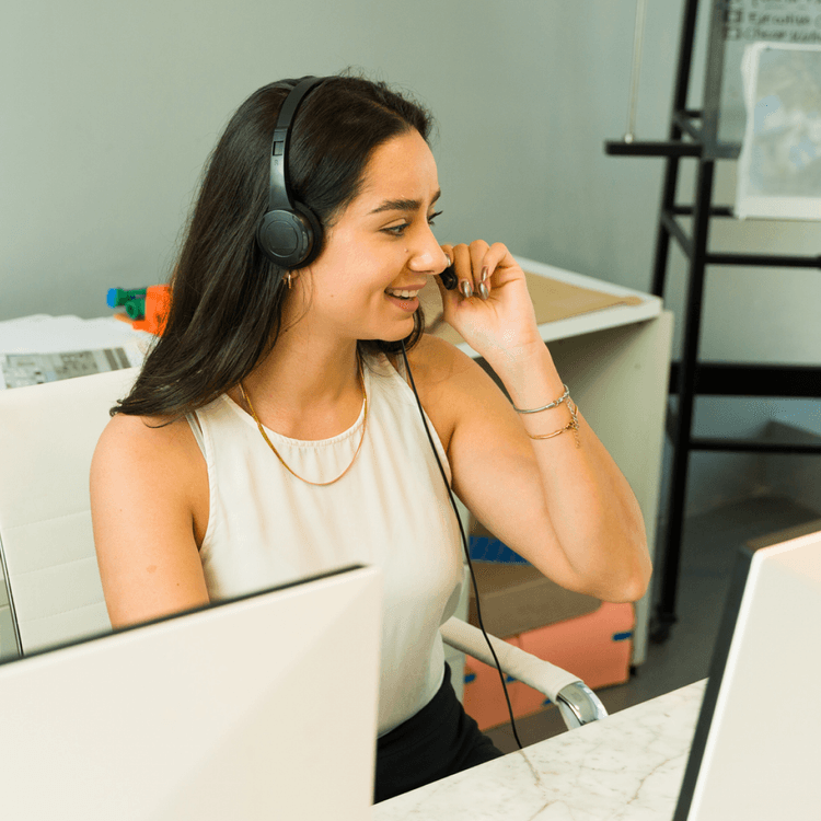 A woman at a desk, speaking on a headset
